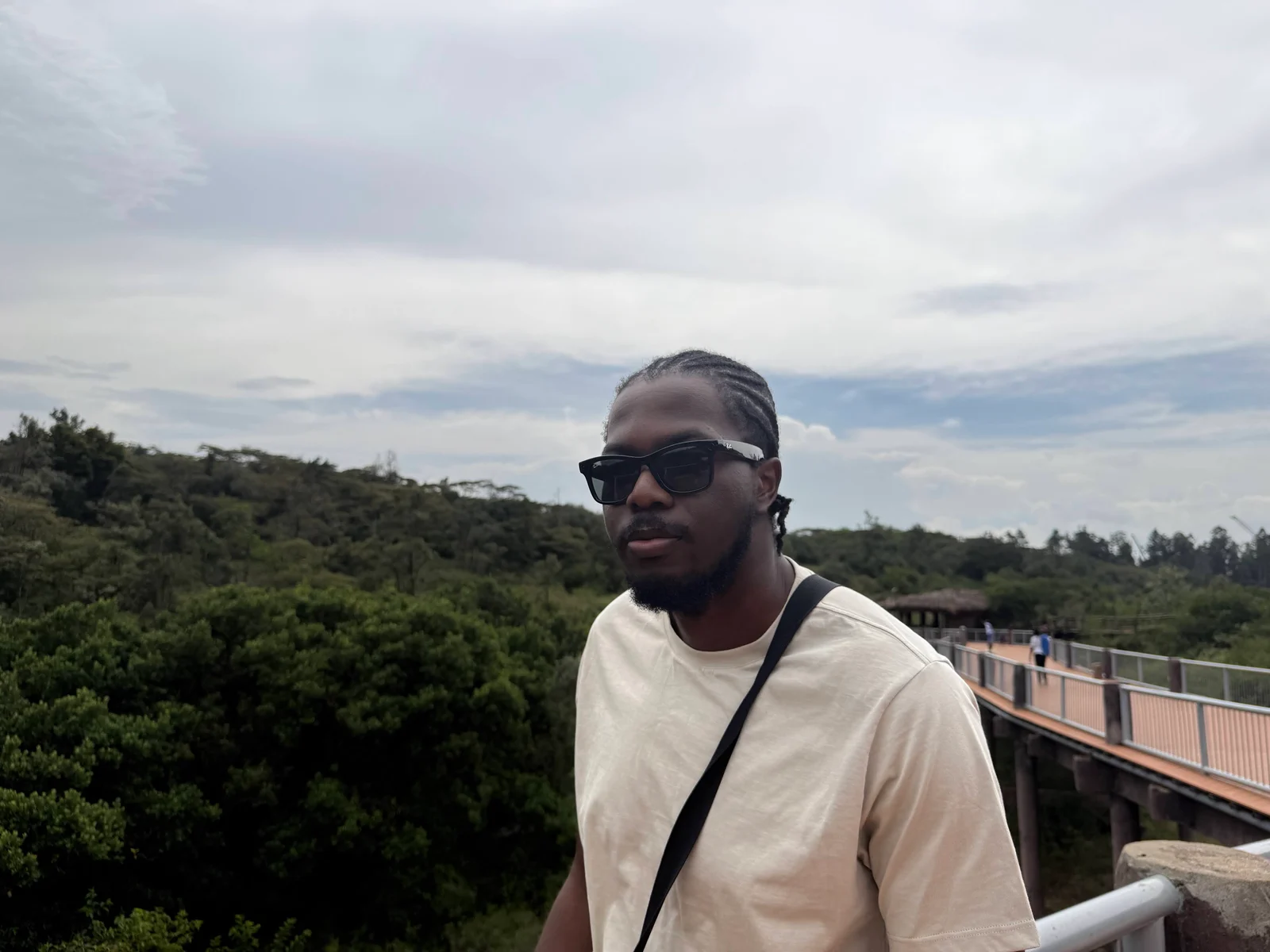 Daniel Abudu wearing sunglasses on a walkway above the trees